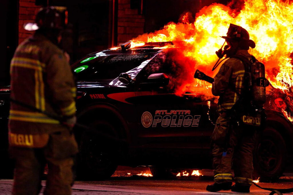 Atlanta riot scene with police car engulfed in flames